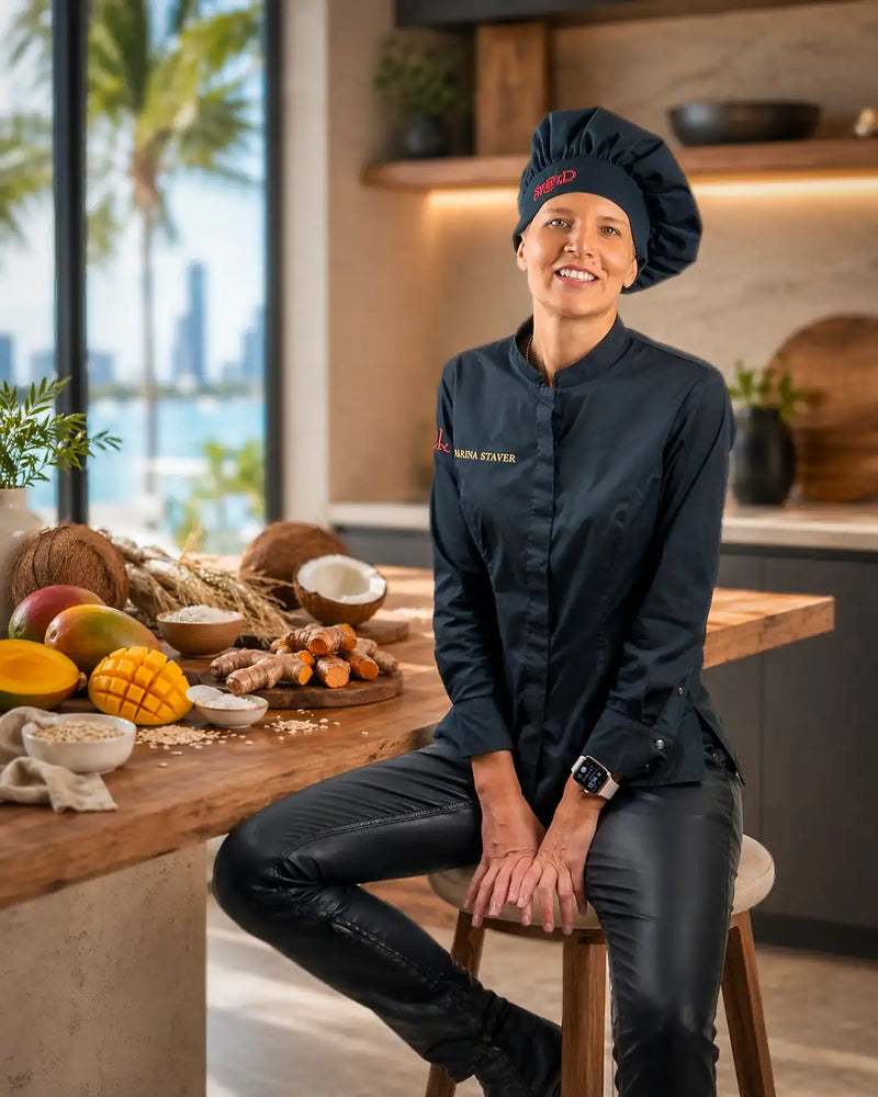 Chef Marina Staver portrait with eye contact in her Miami kitchen, sprouted oats and ingredient spread on the prep counter